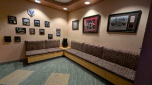 A cozy waiting area at Axelrode Orthodontics featuring L-shaped cushioned seating, framed sports memorabilia, and wall-mounted plaques showcasing achievements.